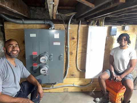 Two Electric Power Pro electricians beside a completed multi-meter service bank